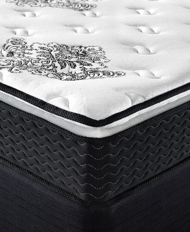 The corner of a mattress. The black base layer has rows of wavy stitching around the perimeter.