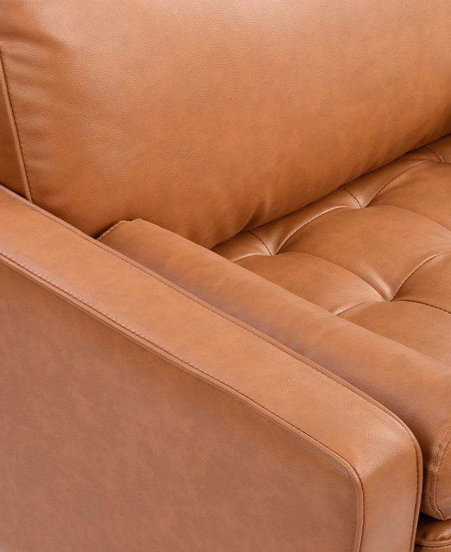 Angled bird's-eye view of a tan armchair. Piping trims adorn the edges of the narrow armrest, seat and back cushions. Angled bird's-eye view of a tan armchair. Piping trims adorn the edges of the narrow armrest, seat and back cushions.