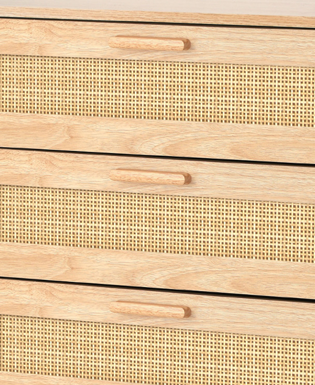 A close up of the front of the drawers highlight the bar handles and the panels of woven rattan.