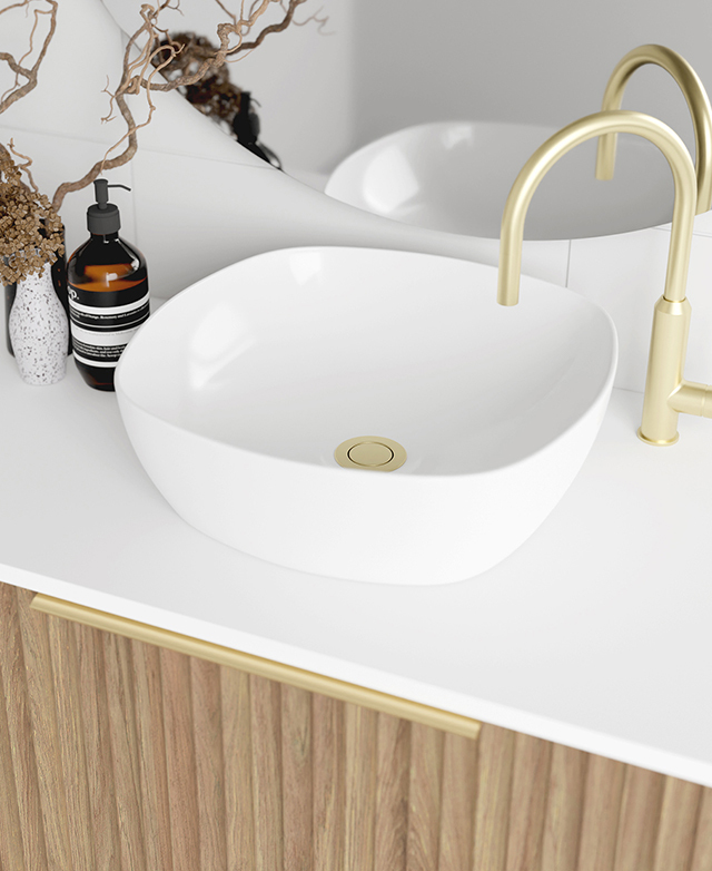 Bird's-eye view of a white vanity with a basin sink and gold tapware styled on top.