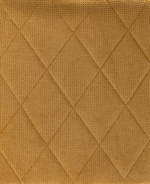 The stitched, tonal diamond pattern on the back of the yellow dining chair is shown close up.