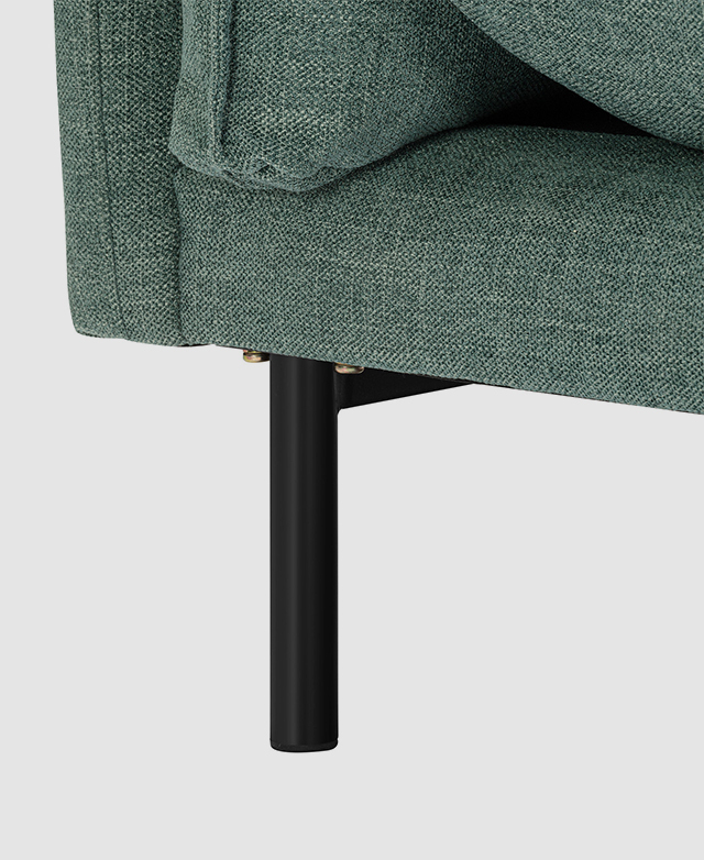 Close-up of a slender, powder-coated steel leg underneath a sofa with blue-green polyester upholstery. Close-up of a slender, powder-coated steel leg underneath a sofa with blue-green polyester upholstery.