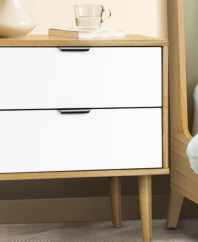 The natural and white variant is styled next to a bed. Sleek, black steel pull handles are at the top of two white drawers.