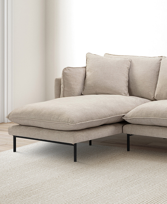 The chaise section is captured from a three-quarter angle. Several cushions are in the corner; black metal legs are shown. The chaise section is captured from a three-quarter angle. Several cushions are in the corner; black metal legs are shown.