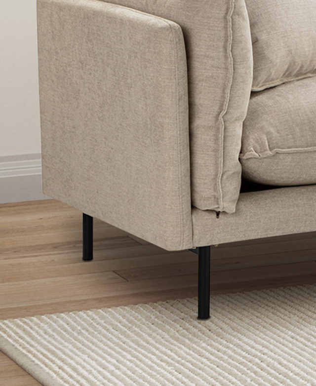 Two of the slender, black, metal legs are accentuated in a close-up snap. One is positioned on top of a cream, textured rug. Two of the slender, black, metal legs are accentuated in a close-up snap. One is positioned on top of a cream, textured rug.