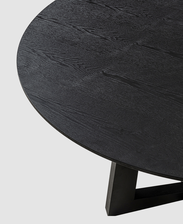 Bird's-eye view of a black round dining table with an oak veneer finish and chamfered edge.