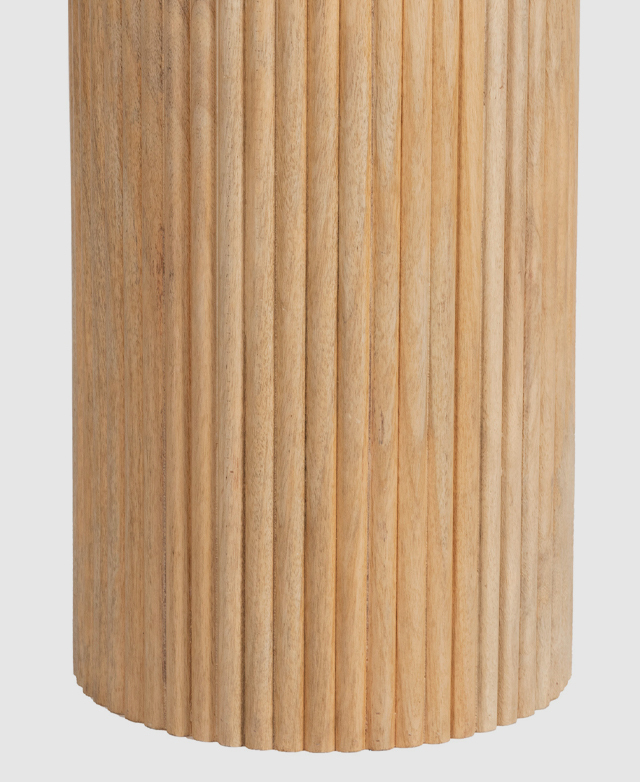 The pedestal base is in focus. Shallow grooves in the round solid mango wood design create a fluted texture.