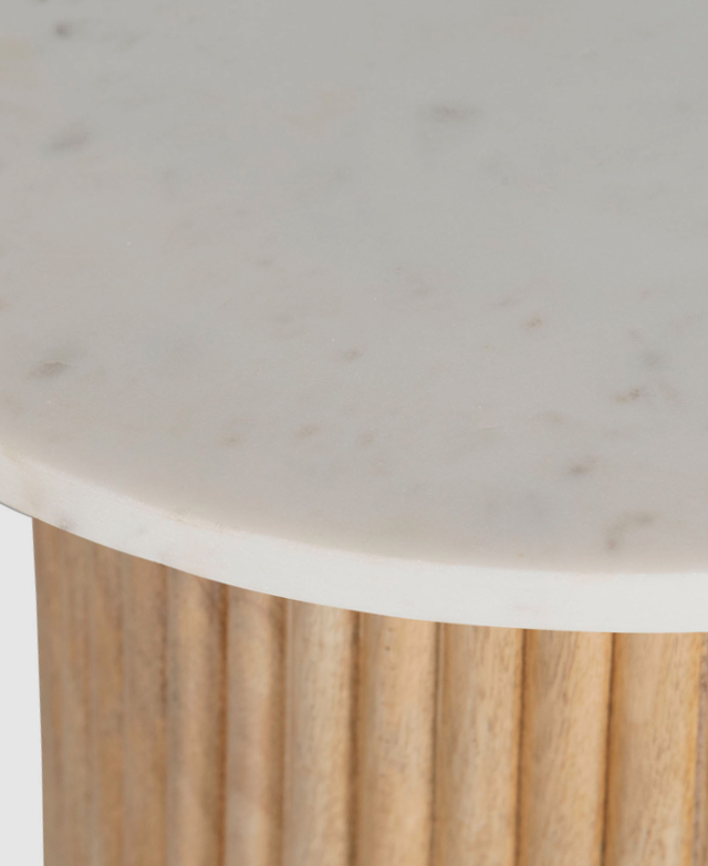 An edge of the genuine marble table top with subtle grey flecks that are characteristic of real stone.