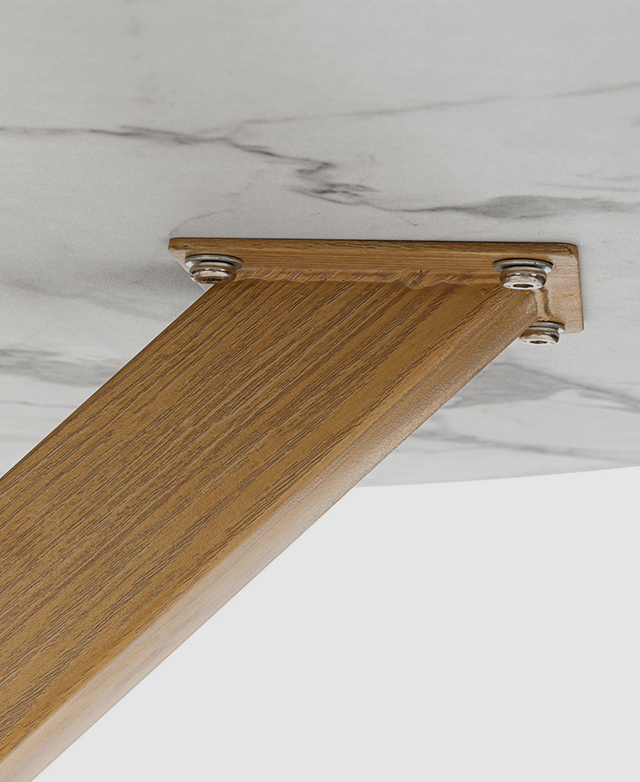 The top of a wood-look metal leg is securely attached to the underside of the marble-look table top. The top of a wood-look metal leg is securely attached to the underside of the marble-look table top.