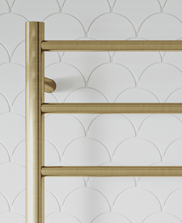 Brushed brass heated towel ladder detail on white scallop tiles.