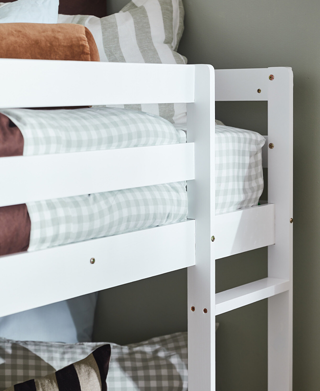Close view of the slatted side bar and steps of the crisp white bunk bed frame. Close view of the slatted side bar and steps of the crisp white bunk bed frame.