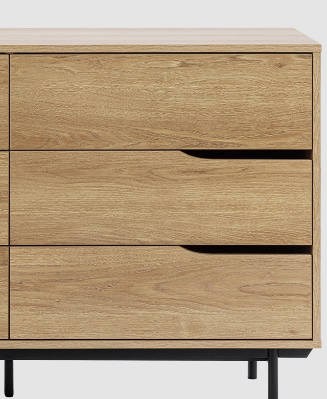 Half of the chest of drawers shown front-on, highlighting the clean silhouette and the cut-out handles.