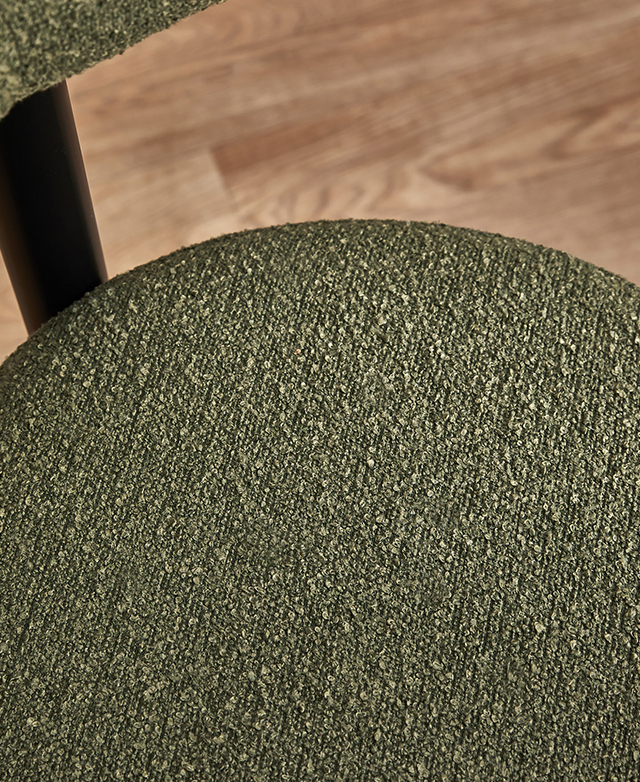 A close up of the rich green boucle upholstery highlights its looped texture.