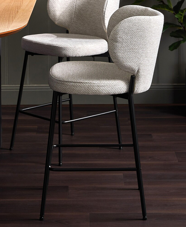 Two bar stools are positioned in front of a bar in an ambient room on a dark floor.