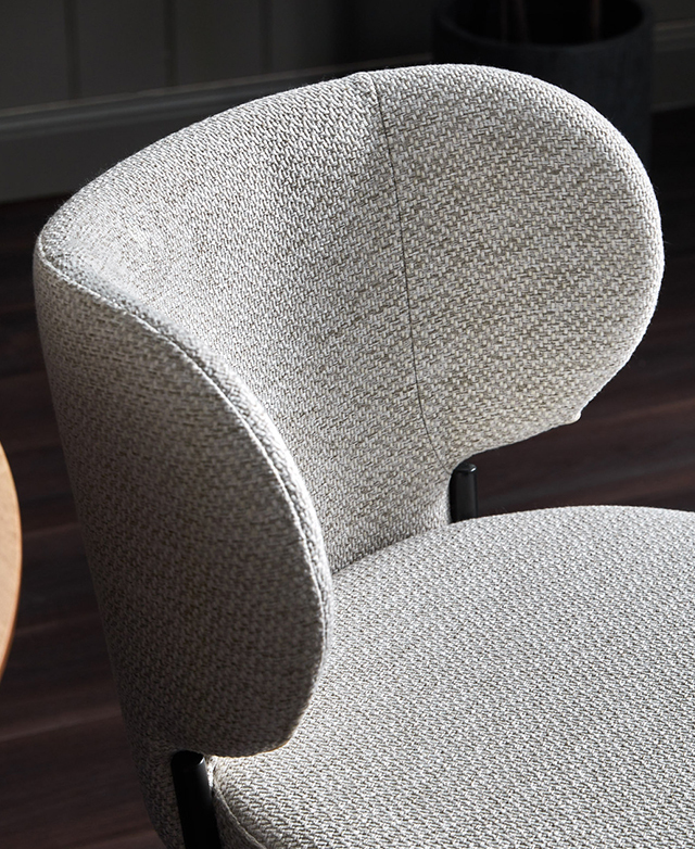 Wingback design of the bar stool seat is upholstered in a woven creamy-grey fabric.