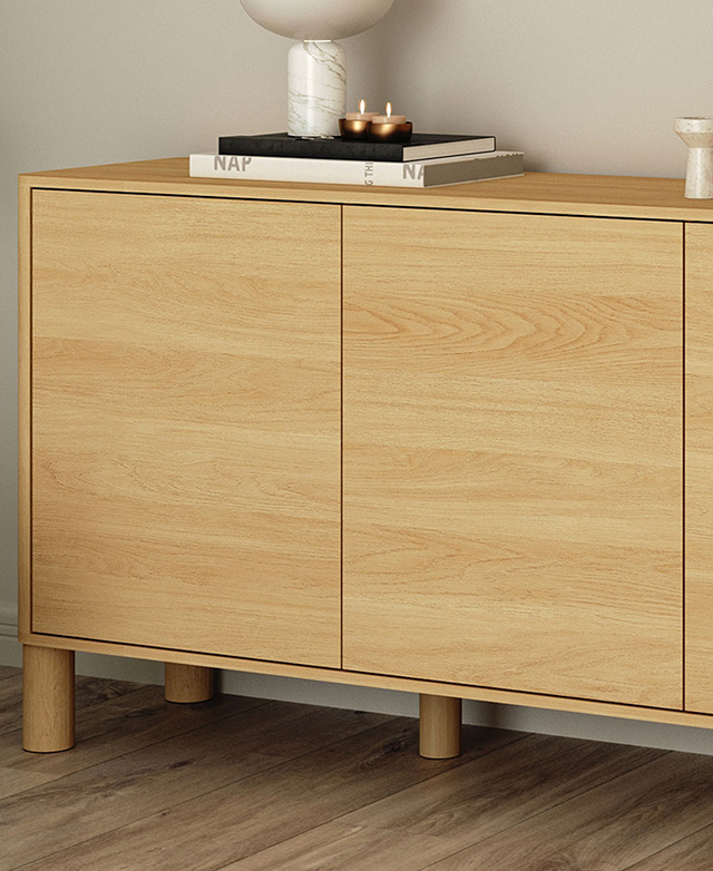 Against a soft cream wall, the sideboard is styled with books, decorative marble objects, and two tealights.