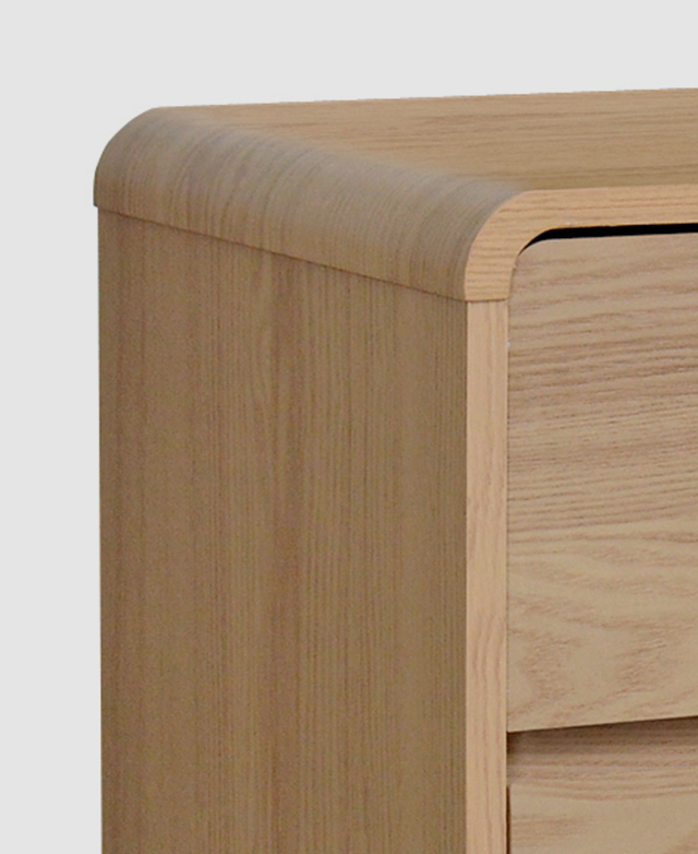 Close view of a waterfall-style top edge of the chest of drawers presents its smooth finish. Close view of a waterfall-style top edge of the chest of drawers presents its smooth finish.
