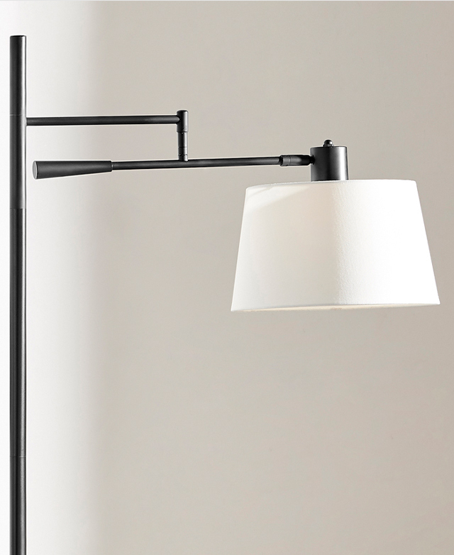 The top half of the floor lamp is in the frame, showcasing the adjustability of the arm that holds the white fabric shade.