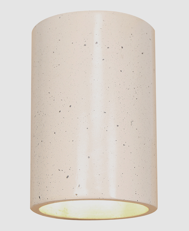 The cylindrical wall sconce is on a white background with the bulb emitting warm light from the bottom.