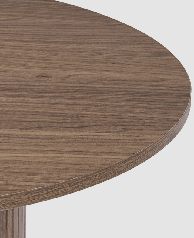 Rich brown-coloured laminate on the round dining table top shows the grain effect.