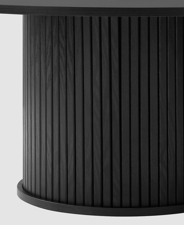 The pedestal base of the black round dining table is zoomed in on to highlight the fluted detail.