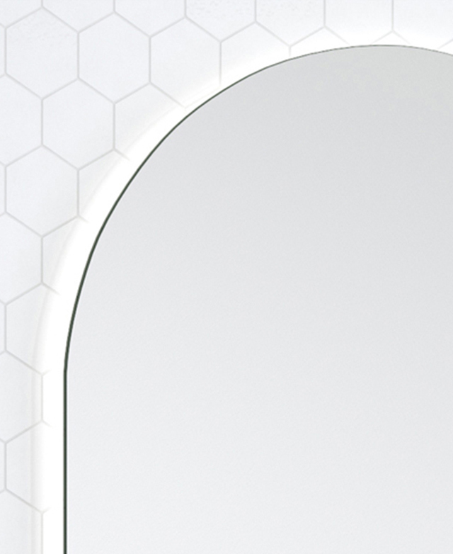 The top edge of the arched frameless mirror is illuminated by an unseen LED strip.