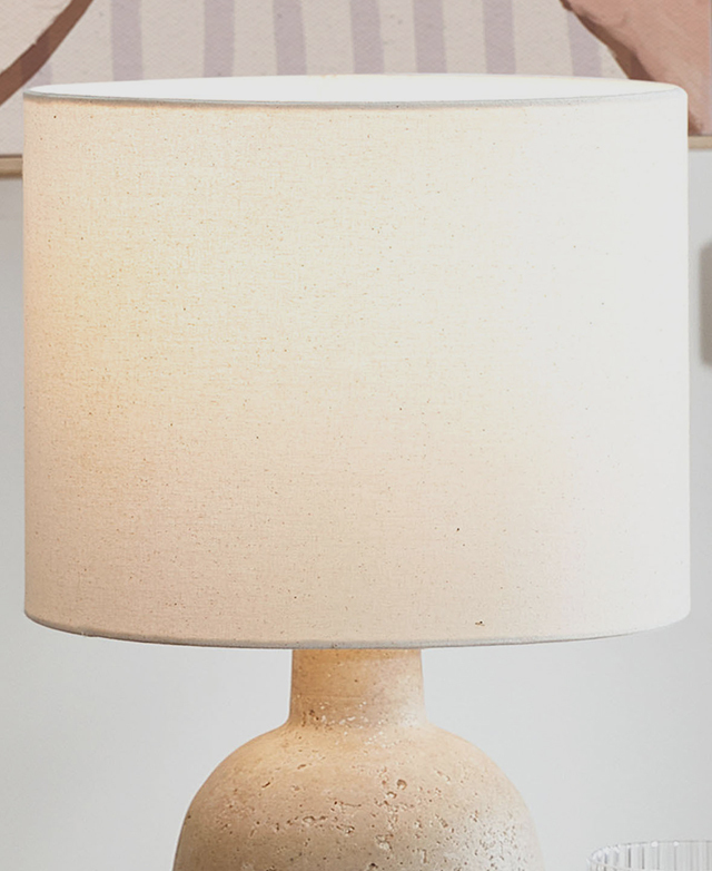 A cool white light is on within the white fabric drum shade.