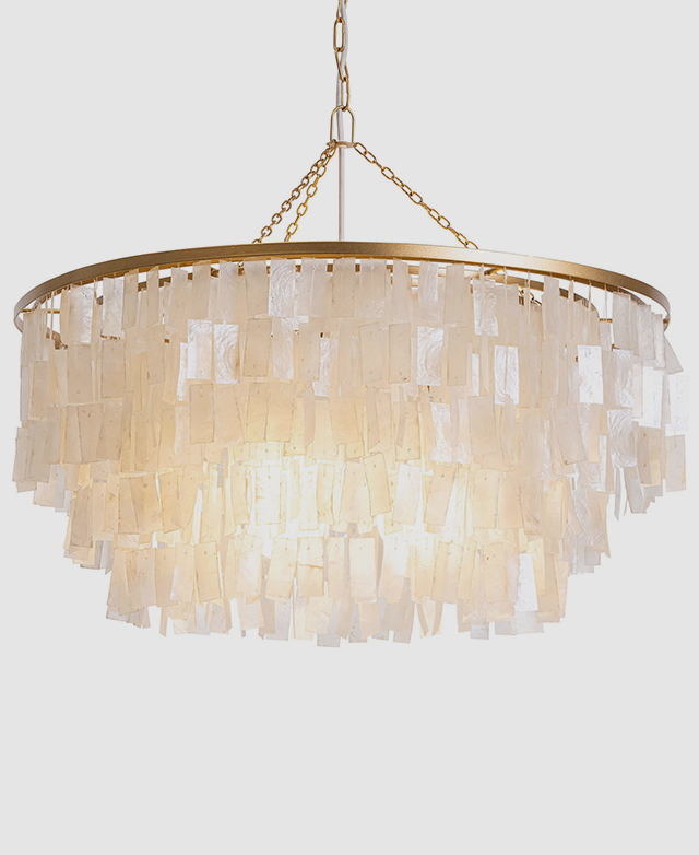 The round pendant light is shown in full, with its metallic frame and layers of capiz shells enhanced by an illuminated bulb. The round pendant light is shown in full, with its metallic frame and layers of capiz shells enhanced by an illuminated bulb.