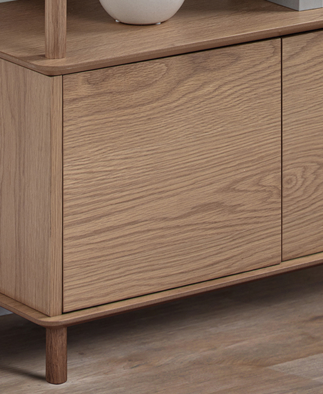 The bottom cupboard portion of the bookcase and its oak wood legs are in the frame. The bottom cupboard portion of the bookcase and its oak wood legs are in the frame.