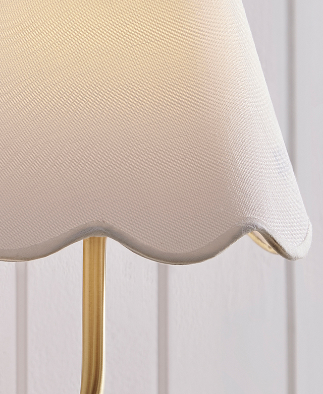 A close up of the bottom edge of the fabric lamp shade highlights the scalloped shape and the smart taped finish.