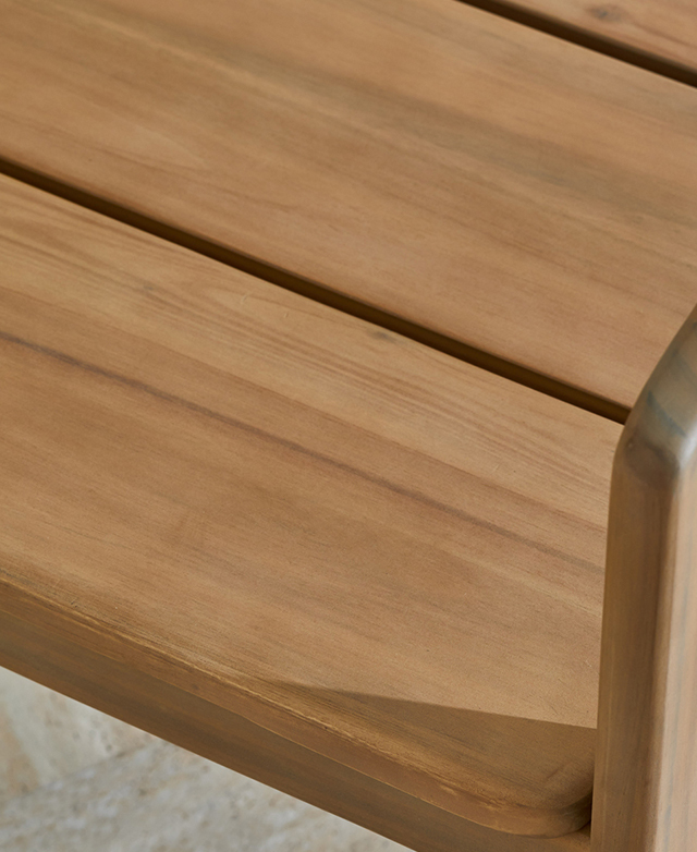 Broad acacia wood slatting forms the dining chair's seat, which is smoothly finished and shown up close.