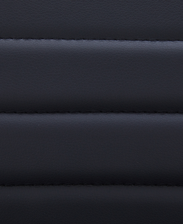 The black faux leather upholstery and channel tufting is magnified.