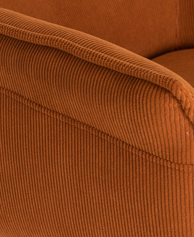 Cropped view highlights the texture of the terracotta corduroy upholstery and the corded piped trim on the armrest.
