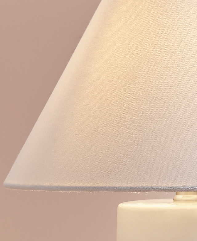 The cropped image displays the soft texture of the white fabric empire lamp shade, with soft light glowing within. The cropped image displays the soft texture of the white fabric empire lamp shade, with soft light glowing within.