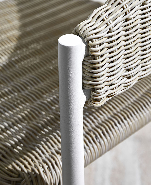 Close view of the chair's armrest draws attention to the powder-coated aluminium frame and the wicker elements.