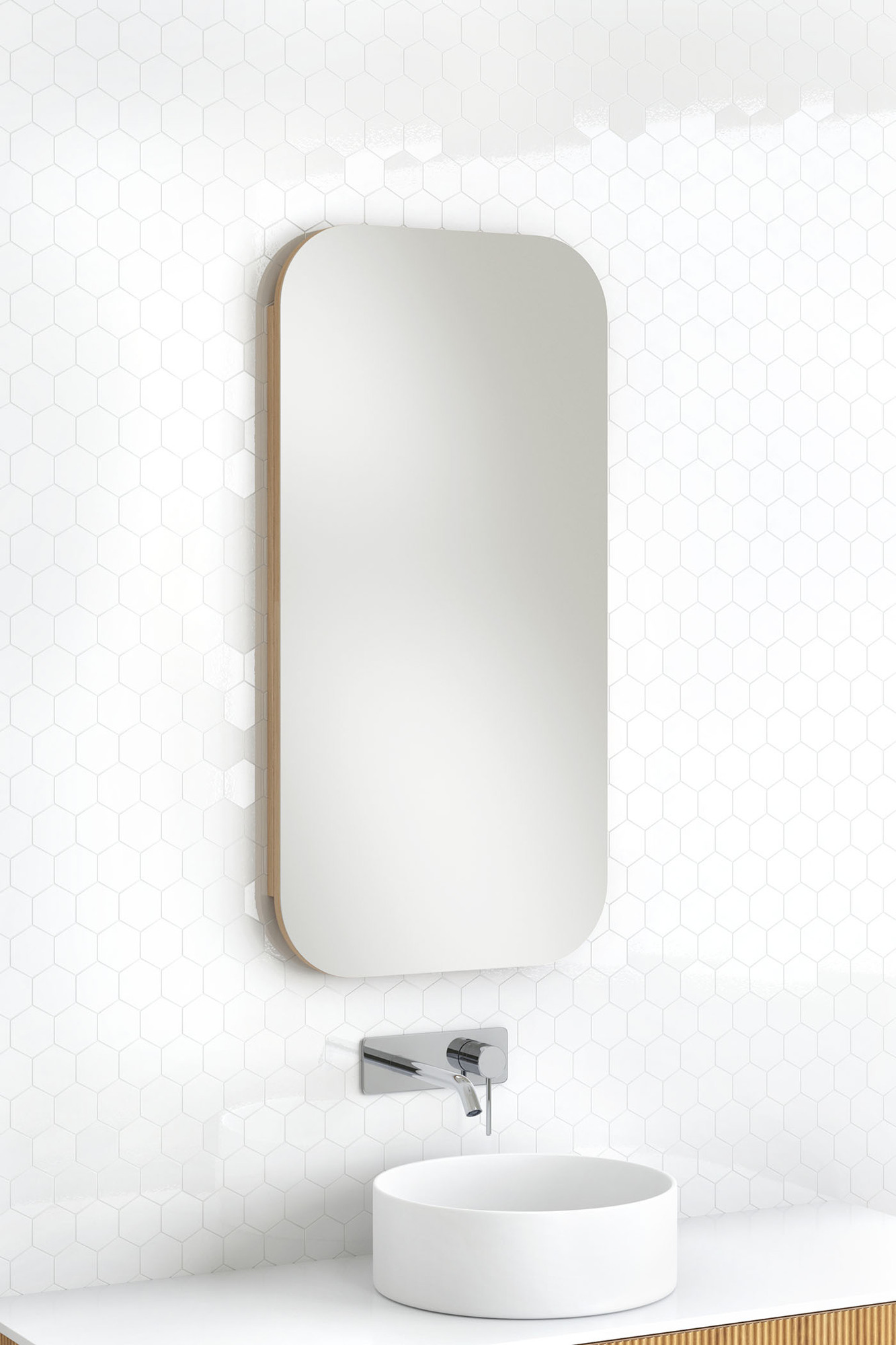 The rectangular mirror is mounted on a white tiled wall above a round white sink.