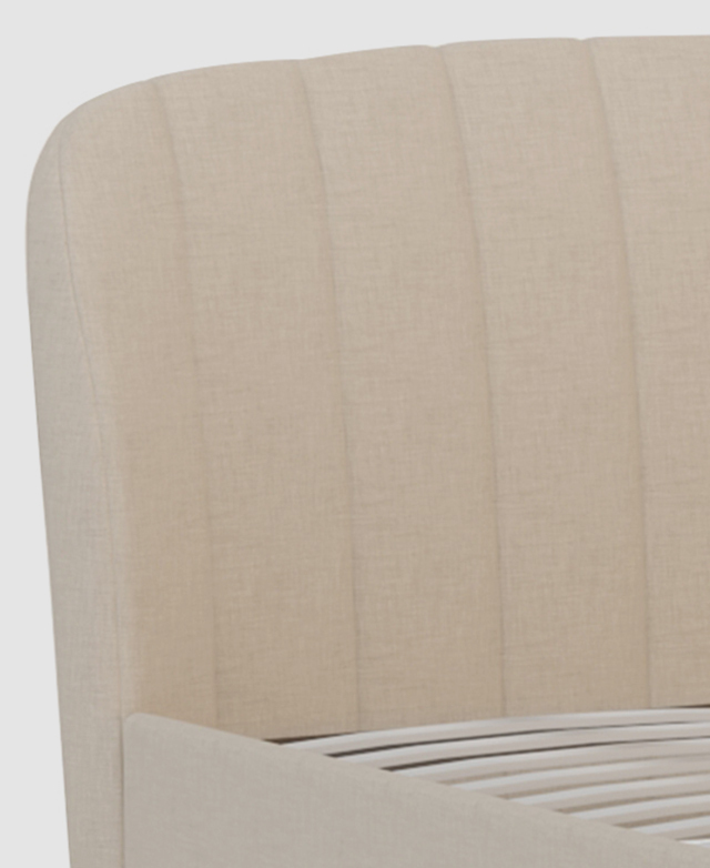 Close up of the cream, linen-look fabric highlights its subtle texture and channel tufting of the bedhead.