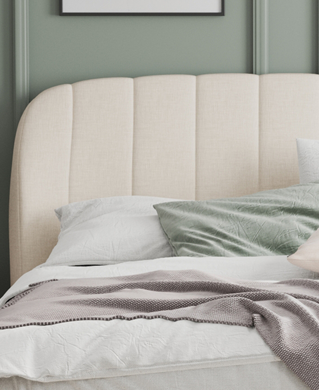 A cropped front view of the bed depicts the tailored look of the channel tufting in front of a sage green wall.
