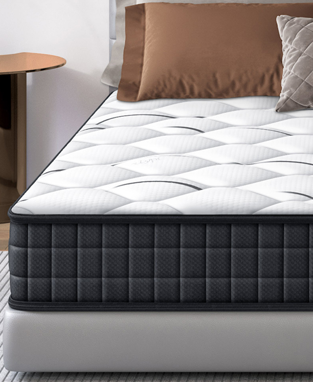 A cropped view shows the mattress from the end on top of a grey bed, highlighting the black trim and generous depth. A cropped view shows the mattress from the end on top of a grey bed, highlighting the black trim and generous depth.