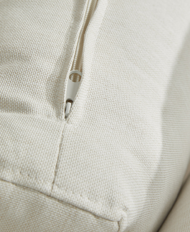 A magnified view of the off-white polyester cushion cover also shows the invisible zipper.