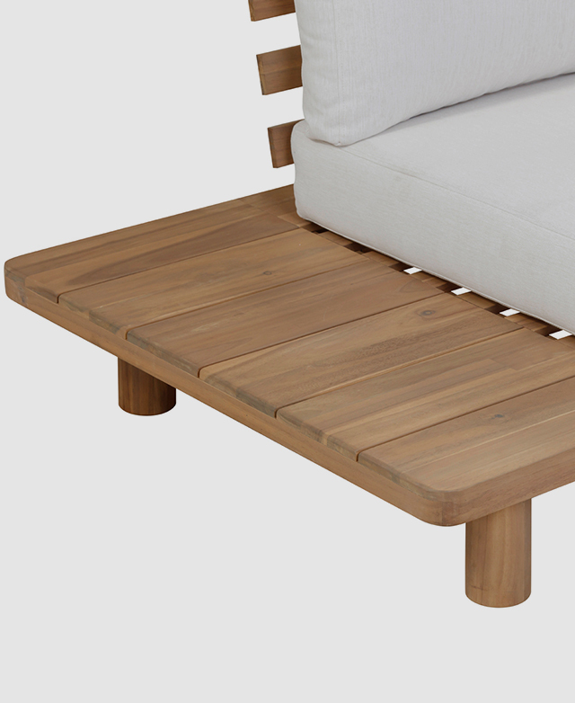 An acacia wood side table is fixed to the end of the sofa, and features a slatted surface and rounded corners.