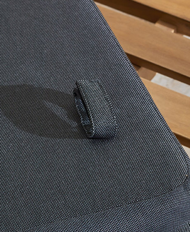 The back of the grey sun lounger cushion has Velcro straps to fasten to the frame, and one is shown. The back of the grey sun lounger cushion has Velcro straps to fasten to the frame, and one is shown.