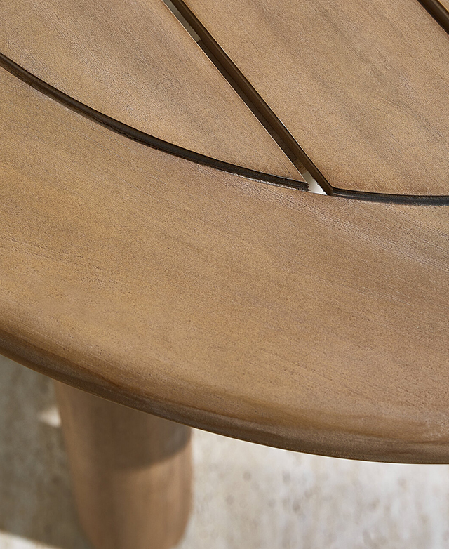 The rounded edge of the smooth acacia wood table is in focus. The rounded edge of the smooth acacia wood table is in focus.
