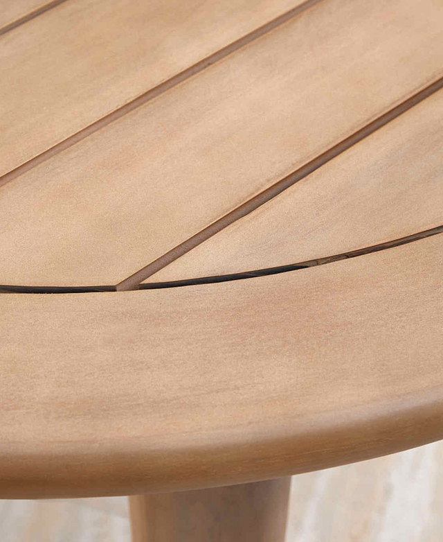 The rounded edge of the smooth acacia wood table is in focus.