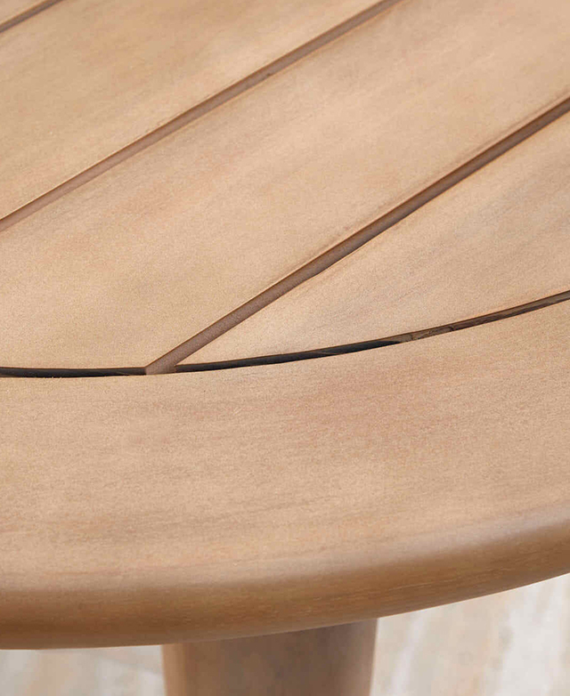 The rounded edge of the smooth acacia wood table is in focus.