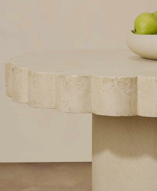 A cropped side view of the coffee table zooms in on the bold scalloped top edge and the shadows it casts. A cropped side view of the coffee table zooms in on the bold scalloped top edge and the shadows it casts.