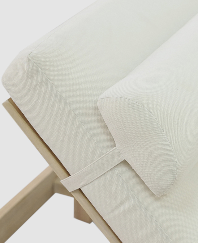 The top of the cushioned cream backrest is straddled by a head cushion, which is securely fastened on.