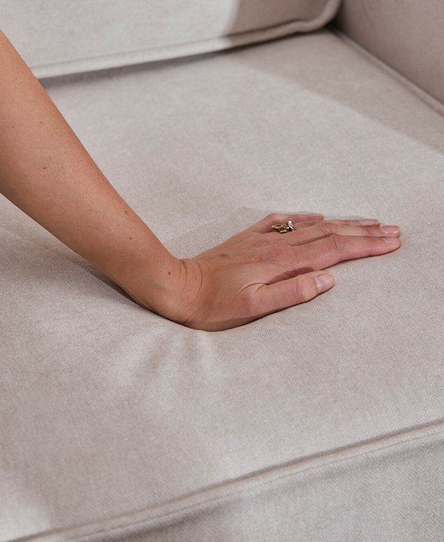 A hand presses onto the surface of the neutral sofa bed.