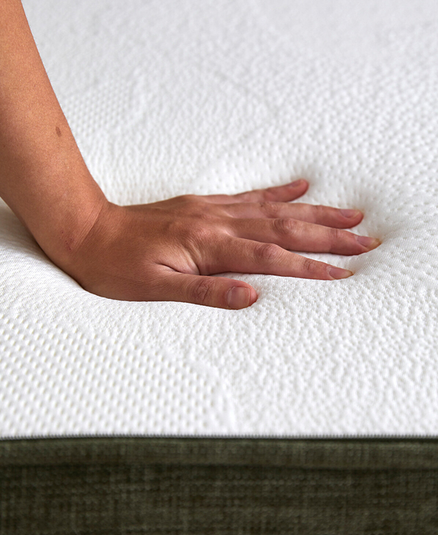 A hand is shown pressing down on the surface of the sofa bed.