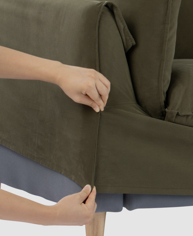Someone is shown applying the green slip cover to the sofa's frame. Someone is shown applying the green slip cover to the sofa's frame.